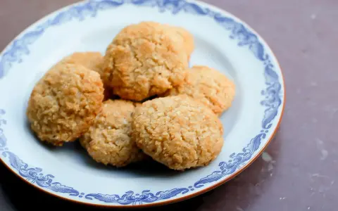 En tallrik med gyllene, glutenfria kakor med kokosflingor. Perfekt för fikat!