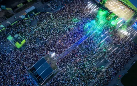 Tłum ludzi na koncercie podczas Łódź Summer Festival 2026. Kolorowe światła i dym tworzą niesamowitą atmosferę.
