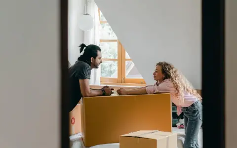 Par diskuterar flytten utomlands, omgivna av flyttkartonger. En checklista för flytten är troligen nära till hands.