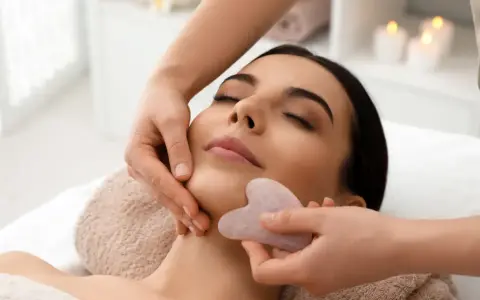 Relaksacyjny masaż twarzy kamieniem gua sha. Delikatne ruchy kamienia poprawiają krążenie i odmładzają skórę.