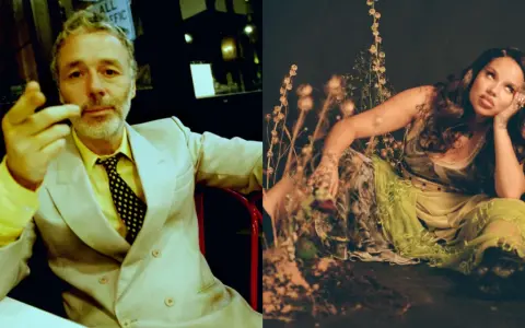 Baxter Dury, aylesbury boy, w żółtym koszuli i garniturze, gestykuluje. Obok Jgrrey w zwiewnej sukni wśród roślin.