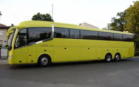 Żółty autokar firmy ANICK stoi na ulicy. Trudno określić, ile miejsc ma autokar, ale wygląda na bardzo pojemny.