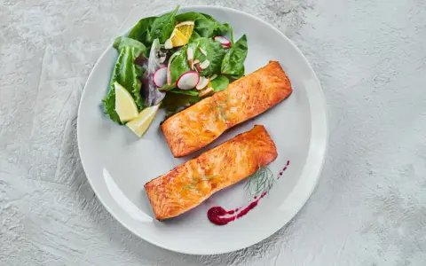 Deux pavés de saumon au four, accompagnés d'une salade fraîche et de quartiers de citron. Un délice simple et savoureux.