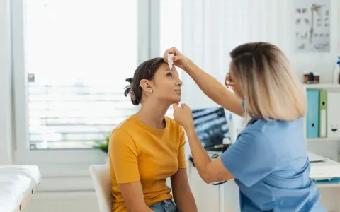 Medico applica cortisone collirio a una giovane paziente in ambulatorio.