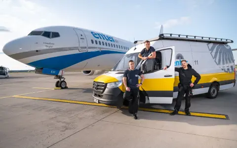 Trzech pracowników Enter Air stoi obok samolotu i vana. Chcesz wiedzieć, jak sprawdzić numer lotu Enter Air?
