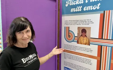 Kvinna i Eddie Meduza-tröja pekar på en utställning om "Flicka i huset mitt emot", en låt av Errol Norstedt.