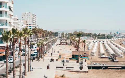 Promenada w Larnace z palmami, białymi budynkami i plażą pełną leżaków. Idealne miejsce, by zobaczyć, co oferuje Larnaka.