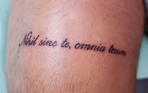 Tatuaż z łacińską sentencją "Nihil sine te, omnia tecum" na skórze.