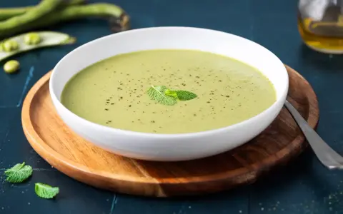 Una ciotola di cremoso purè di fave, guarnito con menta fresca e pepe nero, pronto per essere gustato.