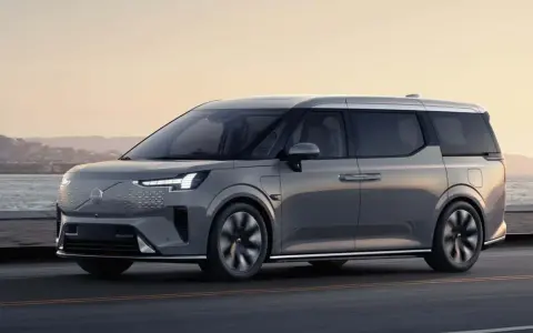 Szary luksusowy van elektryczny Volvo EM90 w ruchu drogowym nad morzem.