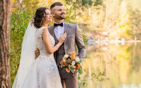 Młoda para w otoczeniu jesiennej przyrody. Ona w sukni ślubnej, on w garniturze. Trzymają bukiet. Zmieniła panieńskie nazwisko.