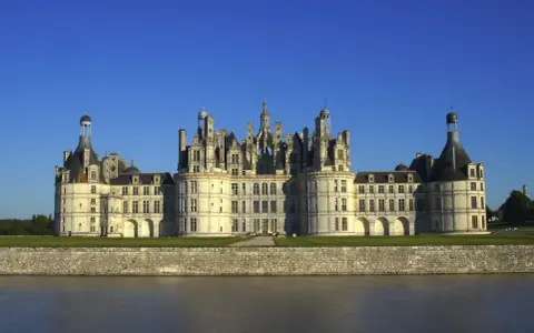 Majestatyczny zamek Chambord, perła Doliny Loary, wznosi się nad spokojną rzeką.