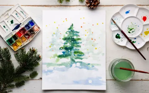 Pintura de acuarela de un árbol de Navidad nevado, con una paleta de acuarelas y pinceles, ideal para una acuarela navidad facil.