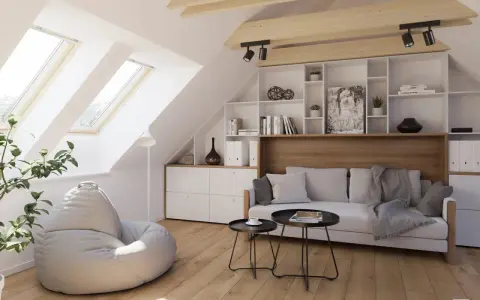 Accogliente salotto in mansarda con divano, pouf, libreria e lucernari che inondano lo spazio di luce.
