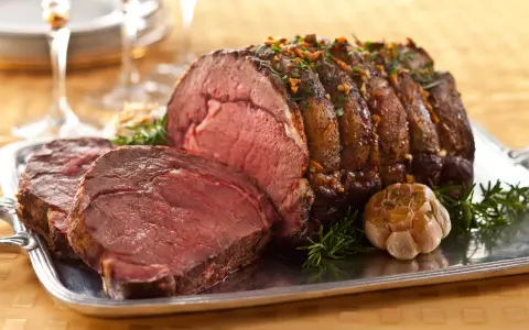 Saftiger Rinderbraten (1 kg) mit perfekter Kerntemperatur, garniert mit Rosmarin und Knoblauch auf einem Silbertablett.