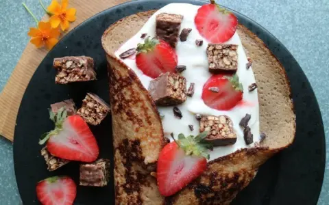 En vikad pannkaka fylld med yoghurt, jordgubbar och chokladbitar. En härlig frukost med nyttiga pannkakor som bas.