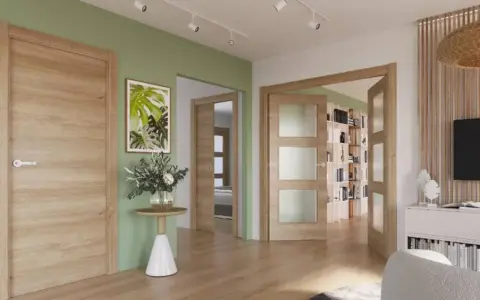 Un pasillo con paredes verde menta y puertas de roble. Un cuadro de hojas tropicales y un jarrón con flores adornan la pared.