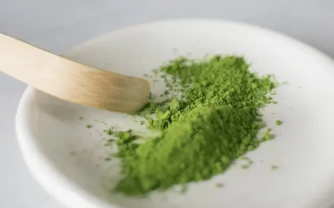 Zielony proszek matcha na białej miseczce, gotowy do przygotowania napoju. Poznaj, jak smakuje matcha – intensywnie, lekko gorzko, z nutą słodyczy.