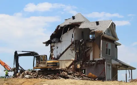 Bagger reißt ein Haus ab. Die Abrisskosten für dieses Haus sind hoch, da es stark beschädigt ist.