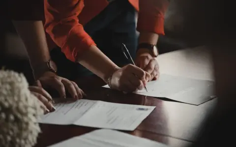 Manos de testigos boda civil firmando documentos importantes.