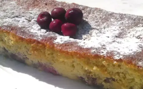 Bizcocho de cerezas casero, espolvoreado con azúcar glas y decorado con cerezas frescas.