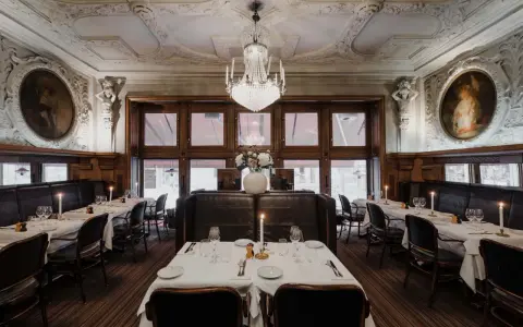 Elegant dukade bord med levande ljus i en av Stockholms gamla restauranger. Kristallkrona och konst pryder taket.