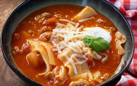 Herzhafte Lasagne Suppe mit Hackfleisch, Nudeln und Käse, garniert mit einem Klecks Sauerrahm und Basilikum.