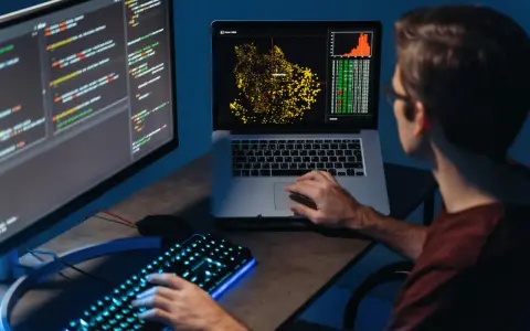 Młody big data engineer analizuje dane na ekranach, tworząc wizualizacje i pisząc kod.