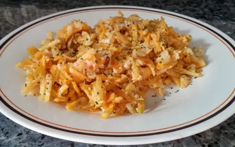 Bacalao dorado desmenuzado con patatas fritas finas y perejil picado, servido en un plato blanco con borde marrón y naranja.