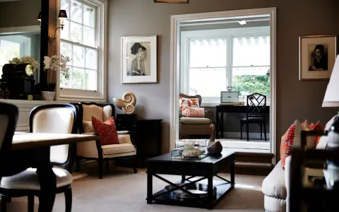 Elegante salón con paredes color topo oscuro, muebles clásicos y obras de arte.
