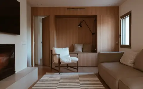 Salones pequeños con mueble de madera integrado, sofá, sillón blanco y alfombra a rayas.