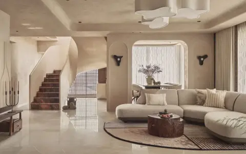Salón con sofá curvo, mesa de centro de tronco y escaleras de mármol. Un espacio con estilo vanguardista y acabados orgánicos.