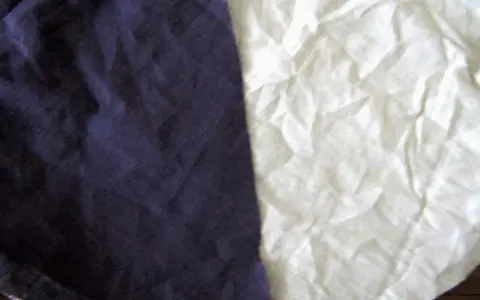 Dwa kawałki materiału, jeden granatowy, drugi biały, przypominają, że **cotton co to** za materiał – miękki i naturalny.