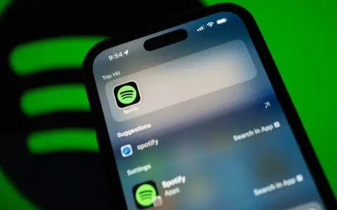 Telefon z aplikacją Spotify, sugerującą muzykę w jakości **spotify lossless**. Zielone logo Spotify w tle.