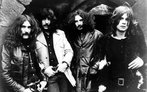 Czterech członków zespołu Black Sabbath, ikony heavy metalu, pozuje do zdjęcia. Ich mroczny styl zapowiadał przełomowe black sabbath albumy.