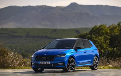 Un Skoda Fabia 130 azul brillante, con techo negro, aparcado en un paisaje montañoso.