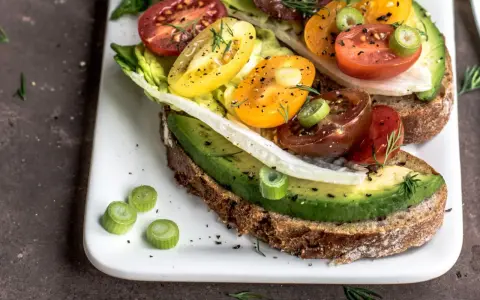 Herzhafte Avocado-Tomaten-Toasts auf Vollkornbrot, garniert mit Frühlingszwiebeln und Dill. Perfekt als kalorienarme Snacks für zwischendurch.