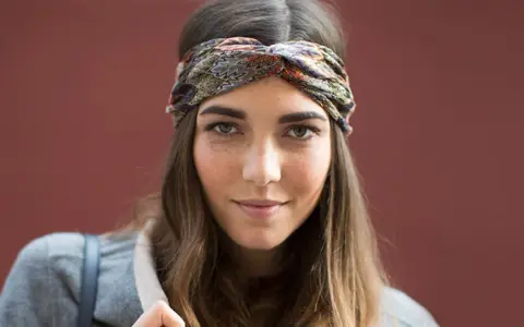 Frau mit braunen Haaren und einem gemusterten Haarband, das ihre Frisur mit Haarband unterstreicht.