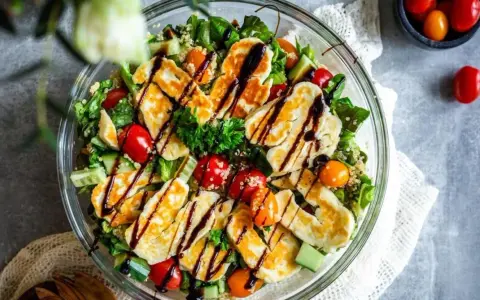 En härlig halloumi sallad med quinoa, körsbärstomater och gurka, ringlad med balsamvinäger. Perfekt för en lätt lunch.