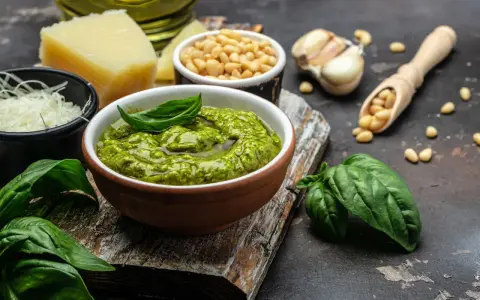 Un tazón de pesto genovés fresco con albahaca, piñones, ajo, queso parmesano y aceite de oliva.