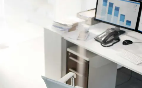 Escritorio con ordenador mostrando gráficos de barras, teléfono, ratón y teclado. La contabilidad y la variacion existencias son clave para analizar estos datos.