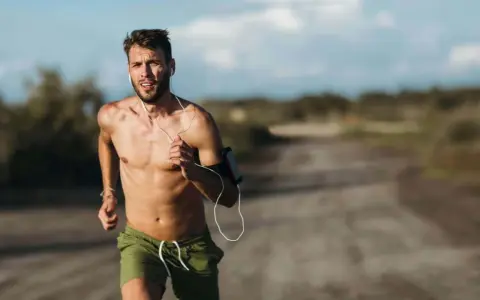 Ein Mann läuft bei Hitze, sein Puls rast. Er trägt Kopfhörer und eine Armbinde für sein Handy.