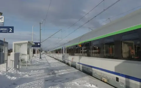 Zimowy peron 2, śnieg i pociąg do Krakowa czekają na pasażerów.