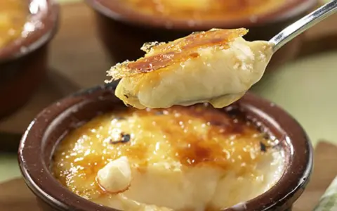 Cremige Crema Catalana Eis wird von einem Löffel aufgetischt, die karamellisierte Kruste bricht.
