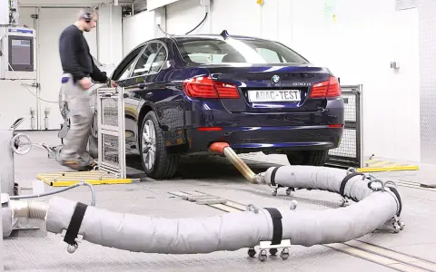 Blauer BMW auf einem Prüfstand für Abgastests. Ein Techniker überwacht die Messungen, die für die Euro 6-Abgasnorm relevant sind.