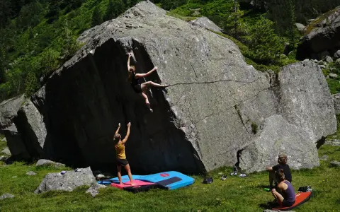 Zwei Frauen klettern an einem Felsen, eine oben, die andere unten. Das ist, was ist bouldern: Klettern ohne Seil an niedrigen Felsen.