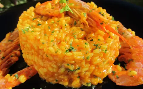 Arroz con gambones, un plato vibrante y delicioso, coronado con gambones jugosos y perejil fresco.