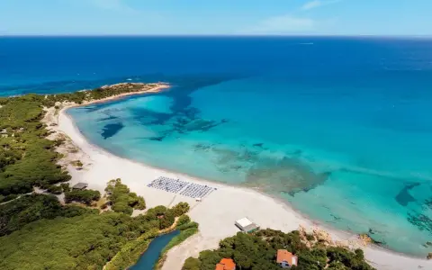 Spiaggia bianca e mare cristallino in Sardegna, ideale per villaggi per famiglie.