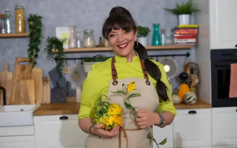 Cristina Catese w kuchni, trzymająca ozdobną dynię i słonecznik.