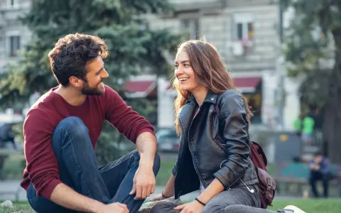 Un couple rit en s'asseyant dehors. Un moment complice pour montrer à son partenaire qu'on a envie de lui.